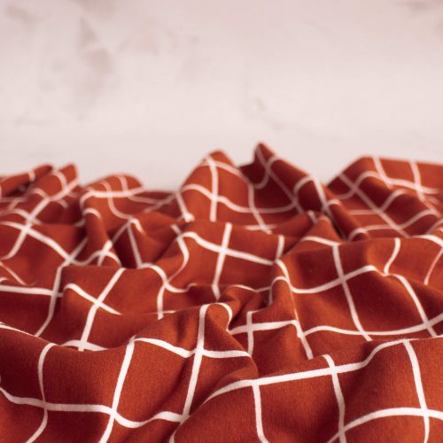 Grid print cotton brushed sweat fabric in terracotta scrunched up