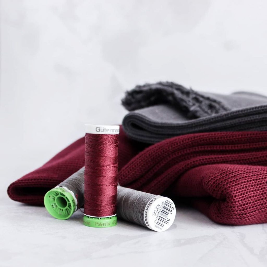 burgundy and grey knit fabrics with matching thread spools