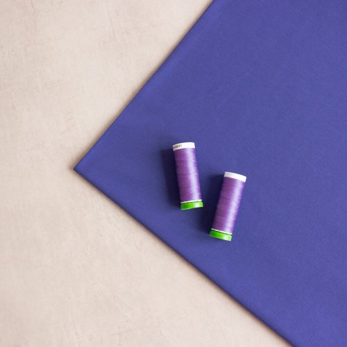 organic cotton jersey fabric in purple with 2 thread spools