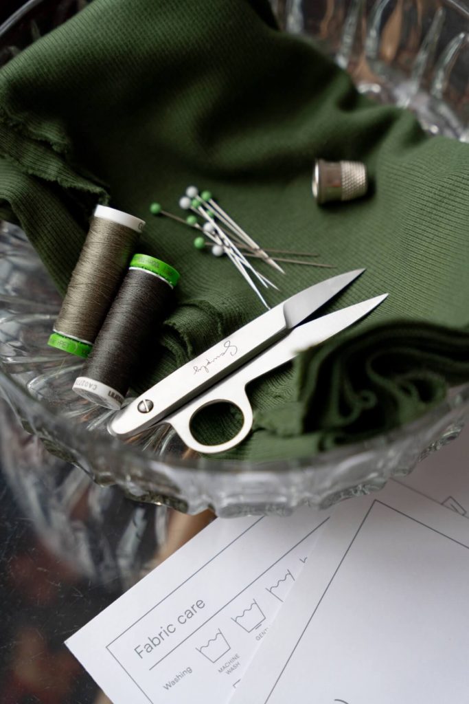 fabrics, spools and pins placed in a bowl