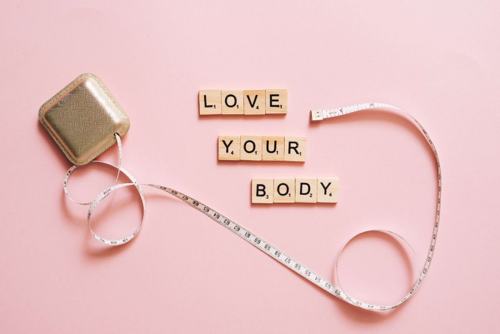 love your body sign with tape measure around on a pink background
