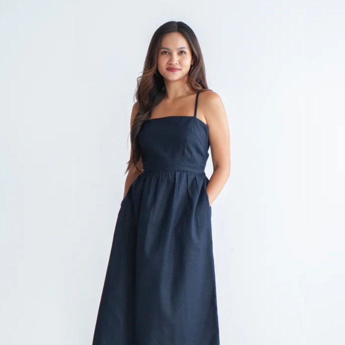 model wearing dark blue sundress with her hands in the pockets