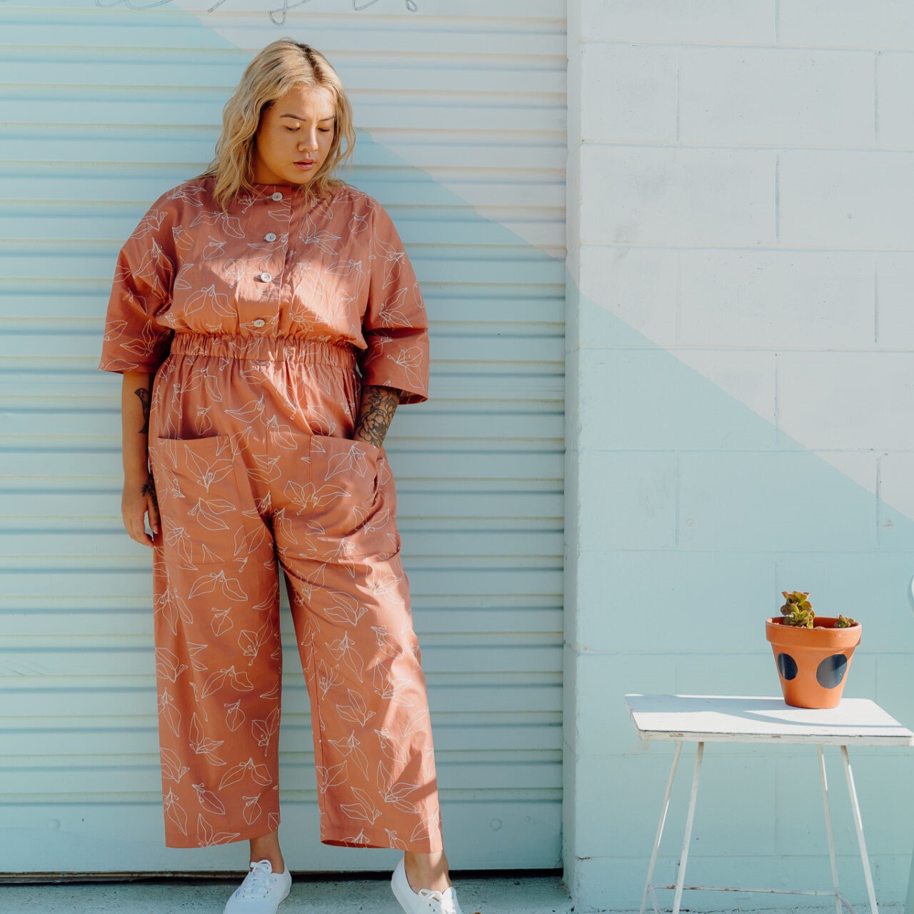 model wearing jumpsuit against blue wall