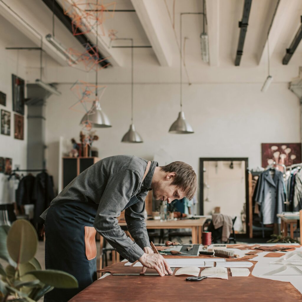 a man creating a men's sewing pattern on a table using tools